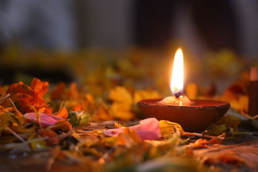 A lit clay diya resting among marigold petals
